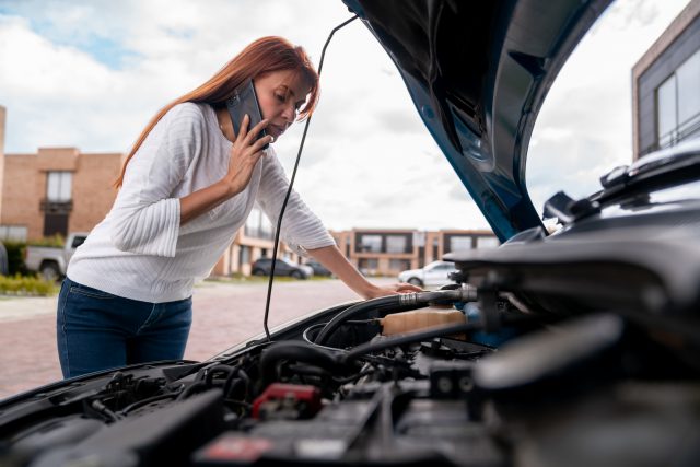 Woman calling the mechanic after her car broke down A woman is calling the mechanic after her car broke down.