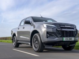 The Top Twenty “Motorway Service Areas” Found Gray Isuzu pickup truck in motion on a two-lane road under a blue sky, from a low-angle side view.