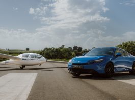 Blue Honda Prelude parked beside a white glider on a sunny airfield runway.
